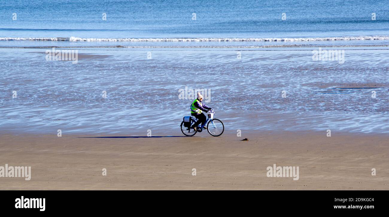 Die Radfahrerin sammelt sich für wohltätige Zwecke (RNLI) am Strand von Filey Stockfoto