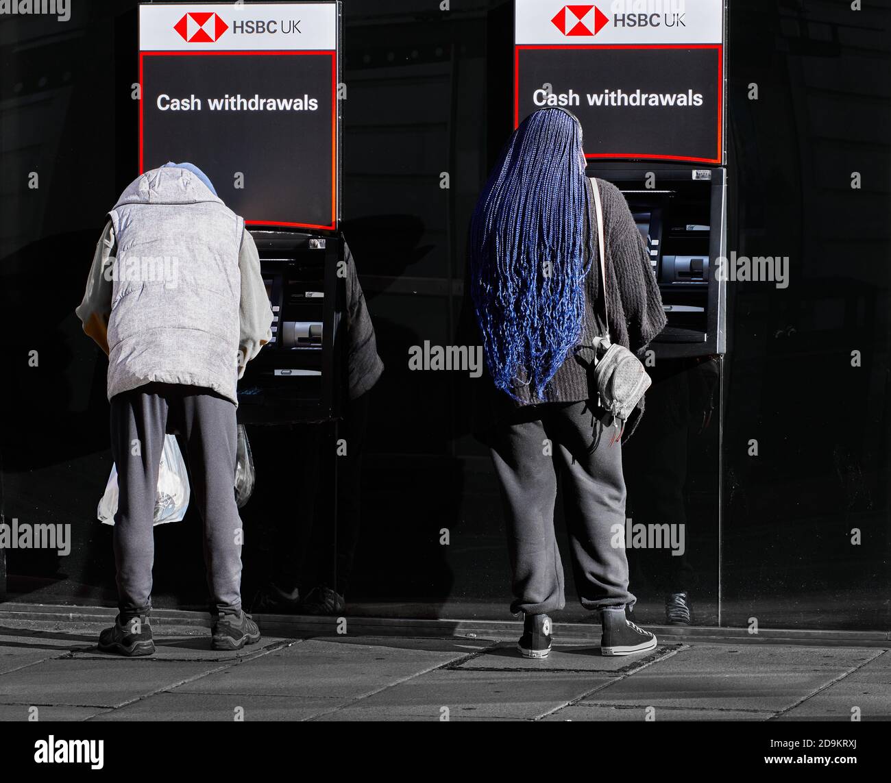 Ein Mann und eine Frau heben Geld an den Geldautomaten der HSBC Bank, Cambridge, England ab. Stockfoto
