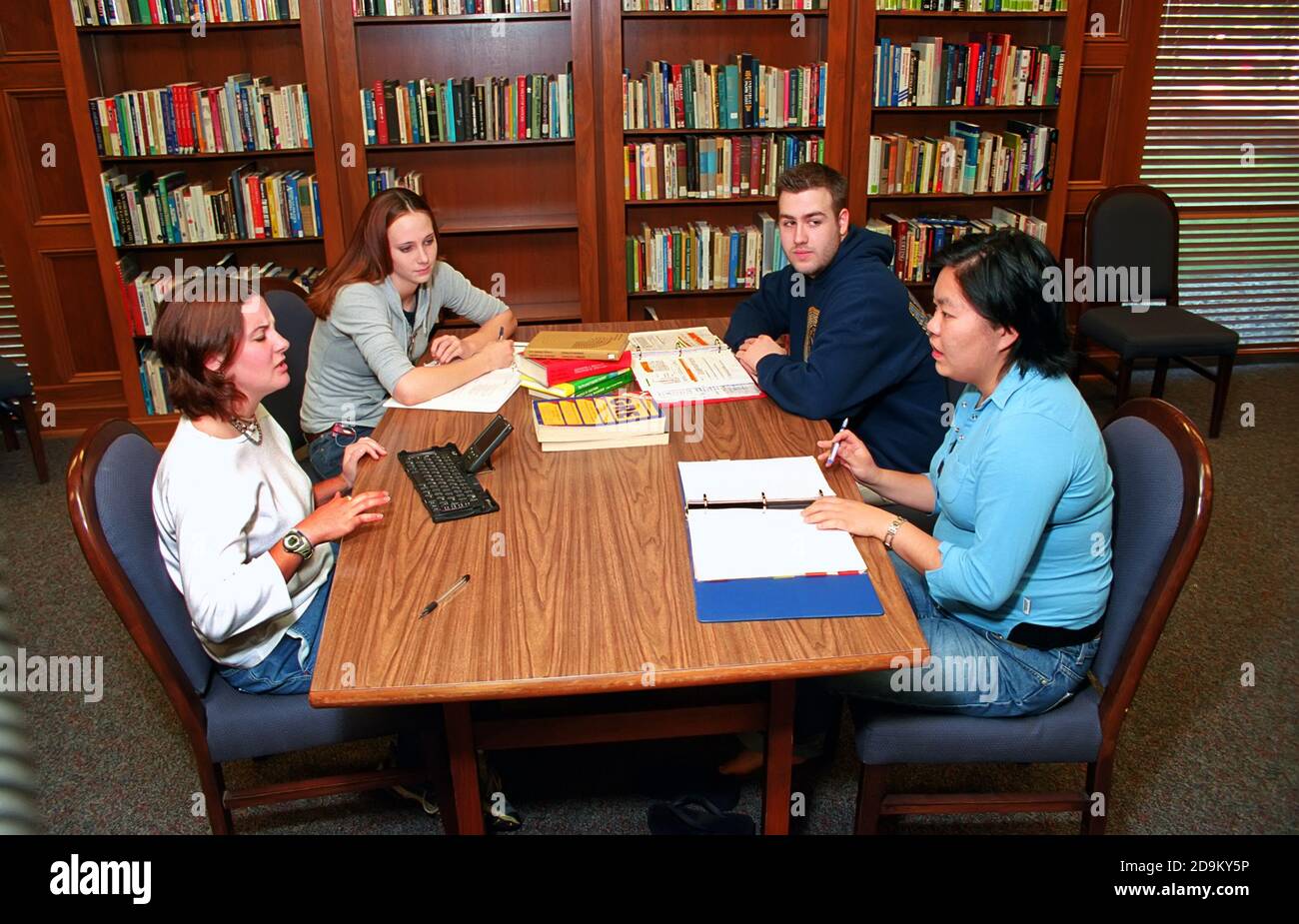 Männliche und weibliche Studenten treffen sich in der Bibliothek zu tun Forschungsarbeit mit Lehramtslehrerin - Computer sichtbar Stockfoto