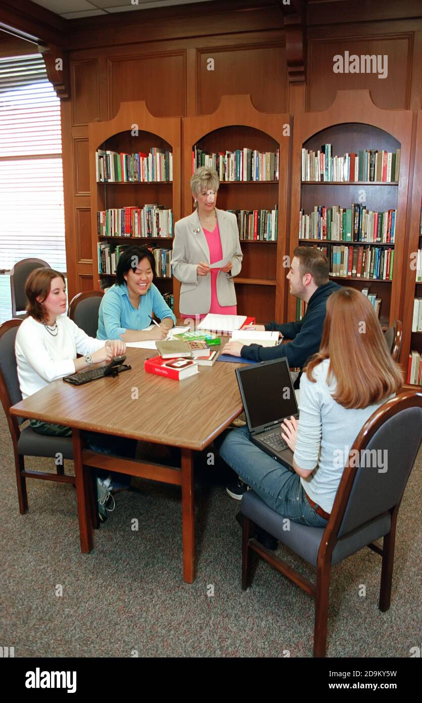 Männliche und weibliche Studenten treffen sich in der Bibliothek zu tun Forschungsarbeit mit Lehramtslehrerin - Computer sichtbar Stockfoto