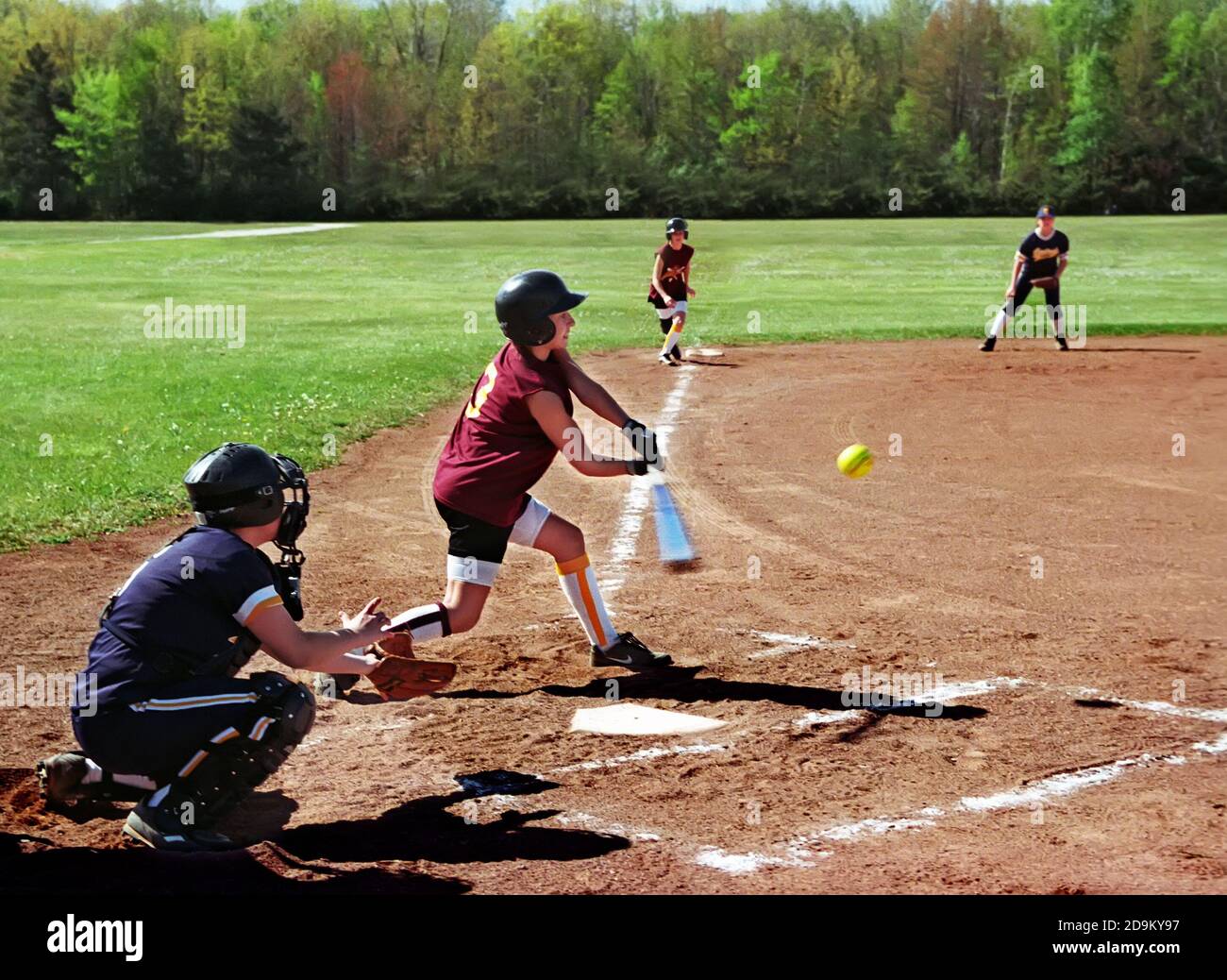 Weibliche Hits Softball während Baseball-Spiel Stockfoto