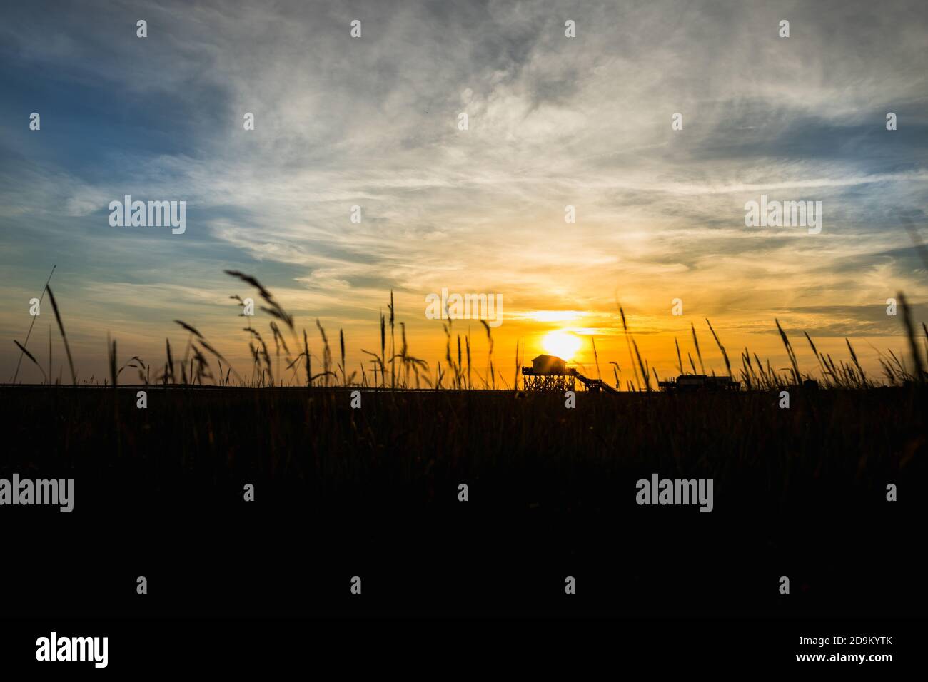 Farbenprächtiger Sonnenuntergang an der Nordsee - im Hintergrund der Sonne ein typisches Stelzenhaus, Pfahlbauten, Pfahlbauten, die den Gezeiten trotzen. Stockfoto