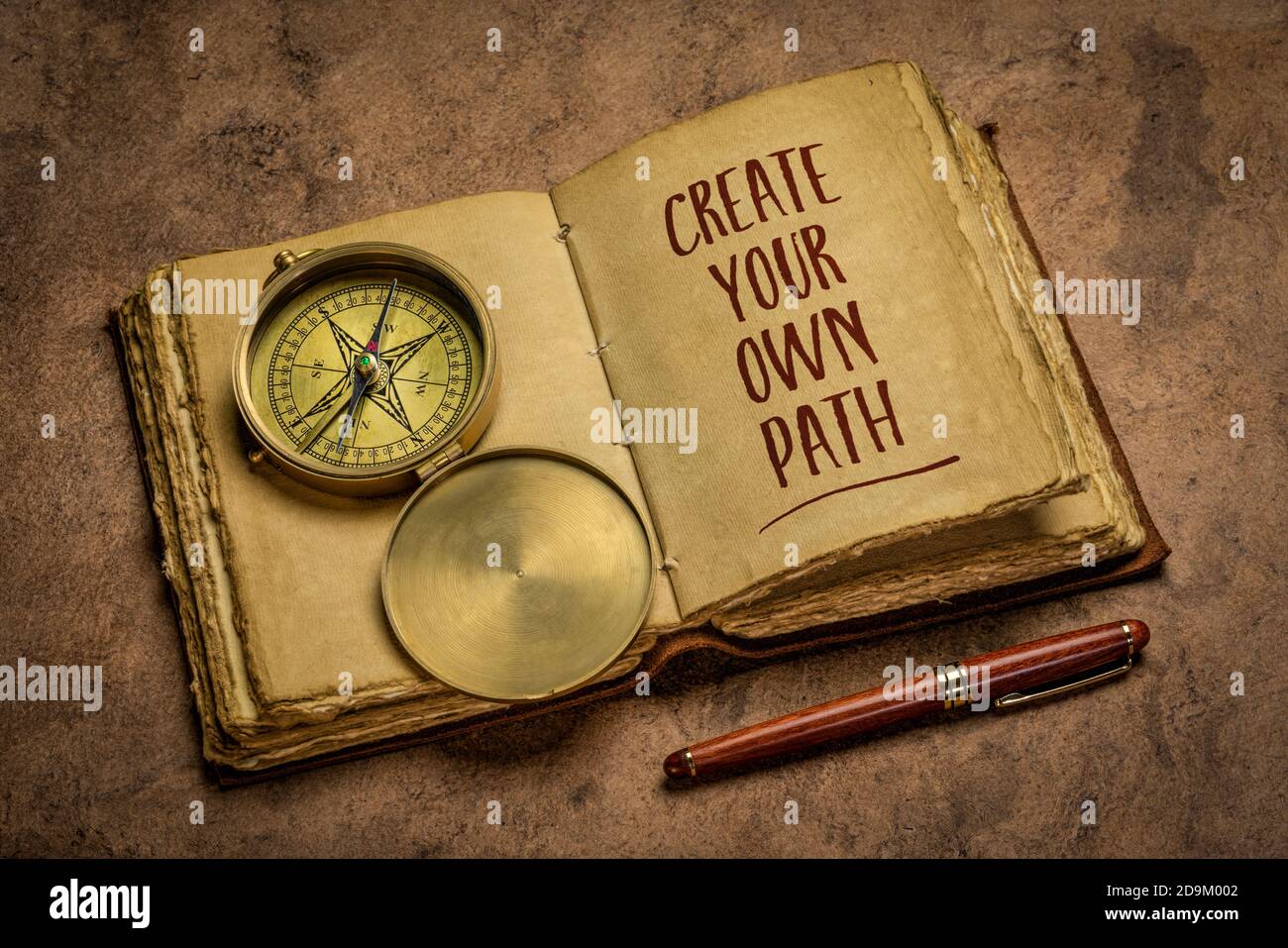 Gestalten Sie Ihren eigenen Weg - Handschrift in einem antiken ledergebundenen Journal mit einem stilvollen Stift und Vintage Messing Kompass, Lifestyle, Karriere und persönliche de Stockfoto