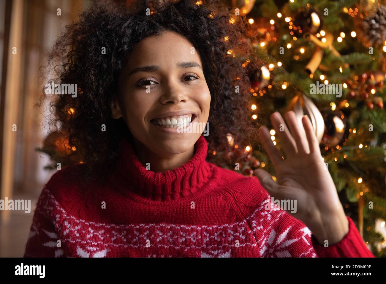 Kopfschuss lächelnde afroamerikanische Frau winkt Hand, Weihnachten zu feiern Stockfoto