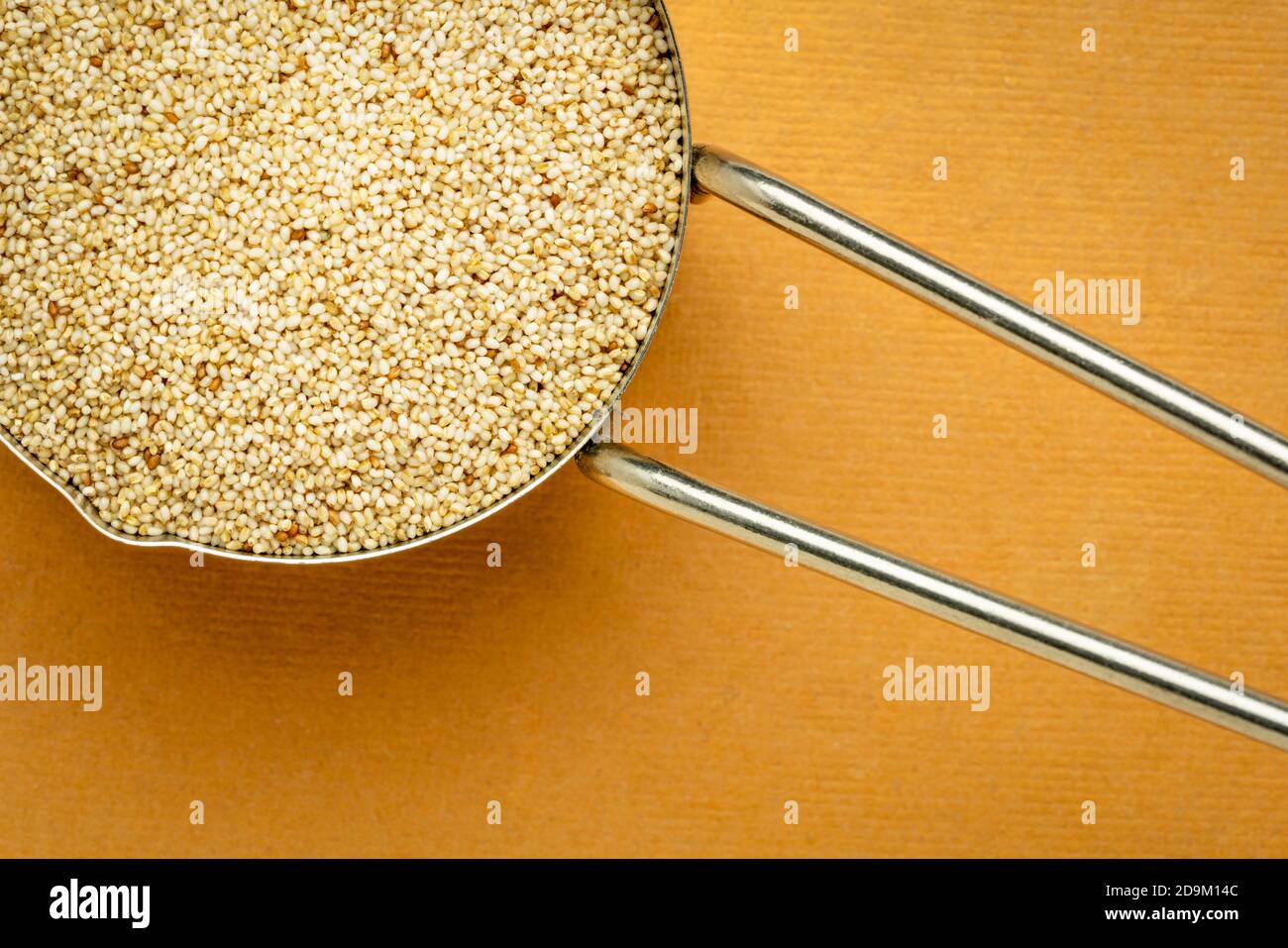 Glutenfreies Elfenbein-Teffkörner in einem Messlöffel aus Metall, Draufsicht gegen handgemachtes Lapppapier, wichtiges Lebensmittelkorn in Äthiopien und Eritrea Stockfoto
