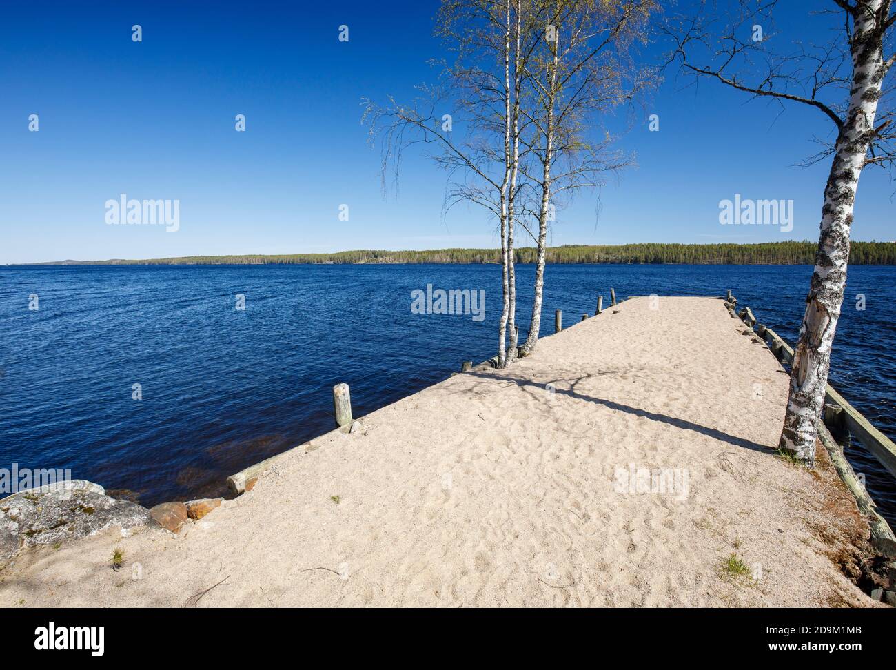 Blick auf den See Iisvesi und den sandbedeckten Pier im Frühling, Finnland Stockfoto