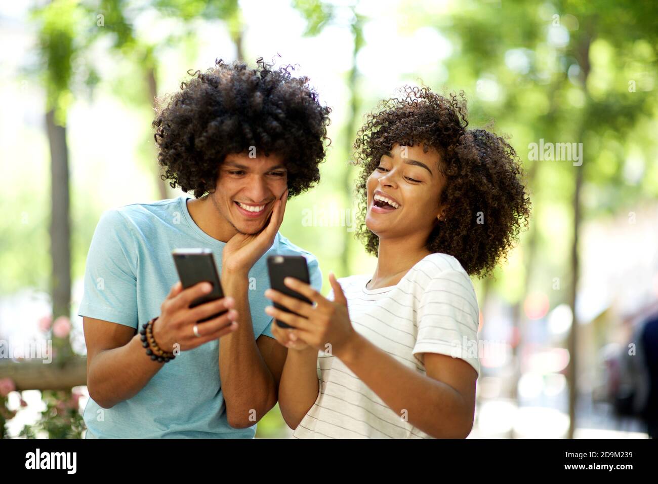 Portrait von zwei Freunden, die Handys draußen betrachten Stockfoto