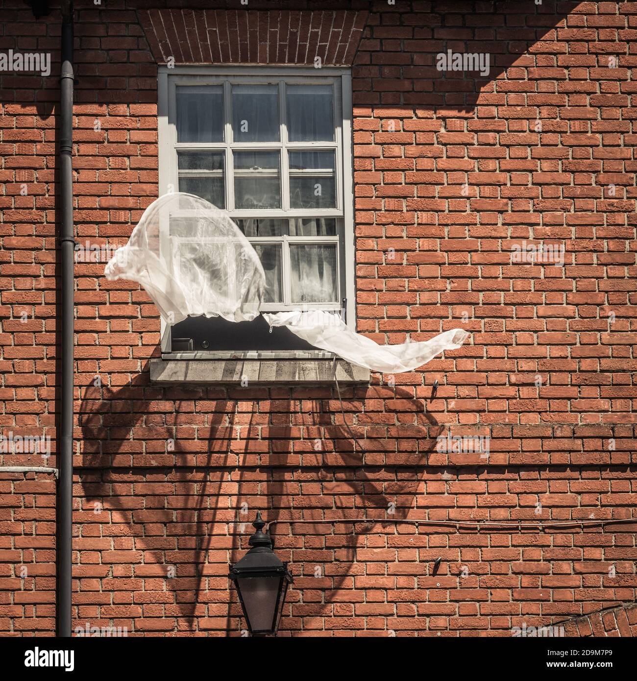 Offenes Fenster mit Netzvorhängen, die im Wind wehen Stockfoto
