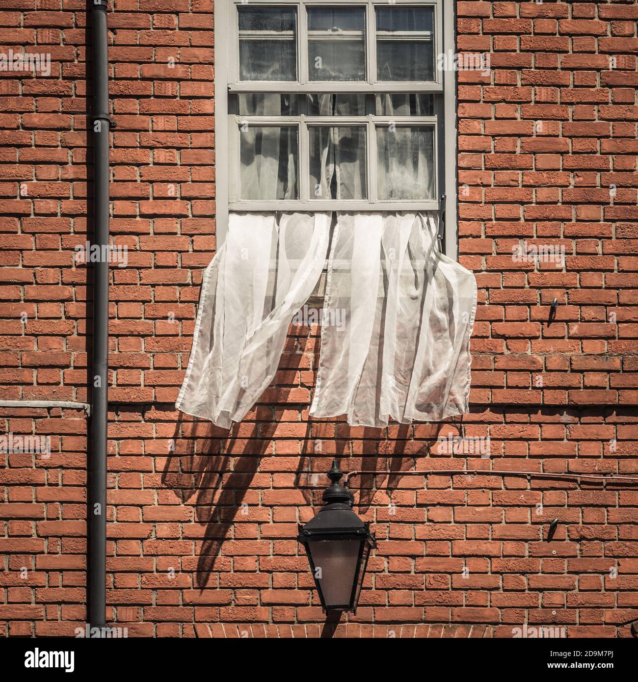 Offenes Fenster mit Netzvorhängen, die im Wind wehen Stockfoto
