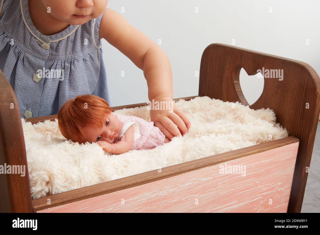 Ein gesichtsloses Mädchen spielt mit einer Puppe. Ins Bett legen. Stockfoto