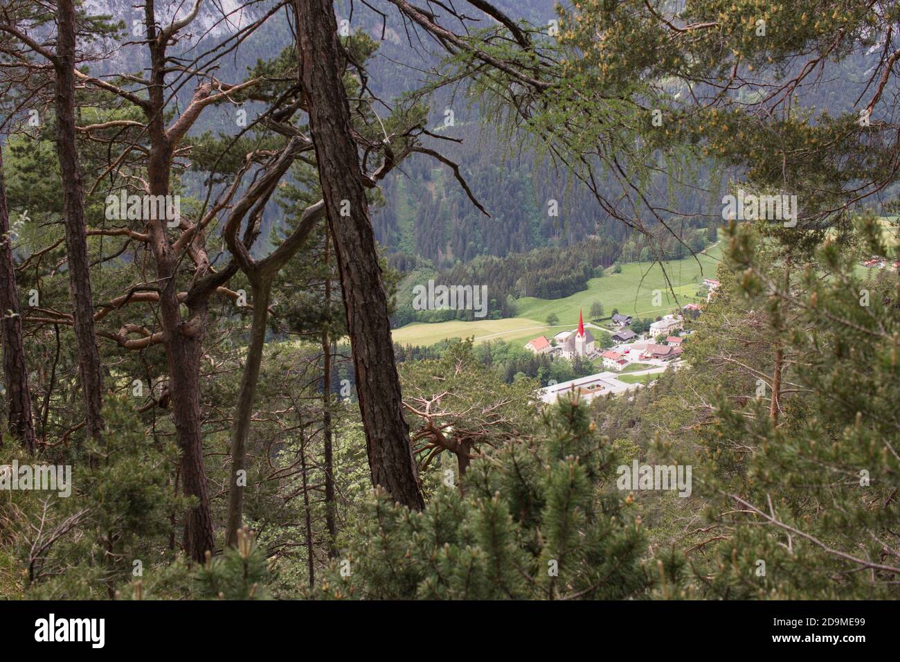 Blick auf ein kleines Bergdorf mit einem roten Kirchturm. Stockfoto