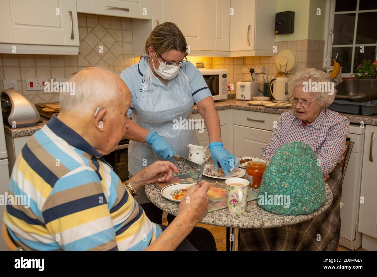 Ein älteres Paar in den 80ern bei sich zu Hause, das während der Sperre des Coronavirus-Pandemievirus Tee von einem Sozialarbeiter serviert, England, Vereinigtes Königreich Stockfoto