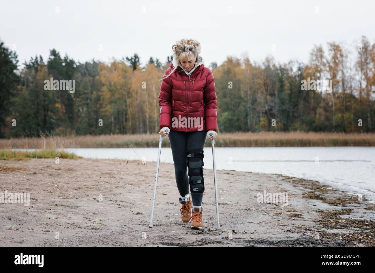 Verletzte Frau, die mit Krücken am Strand geht und nachdenklich aussieht  Stockfotografie - Alamy