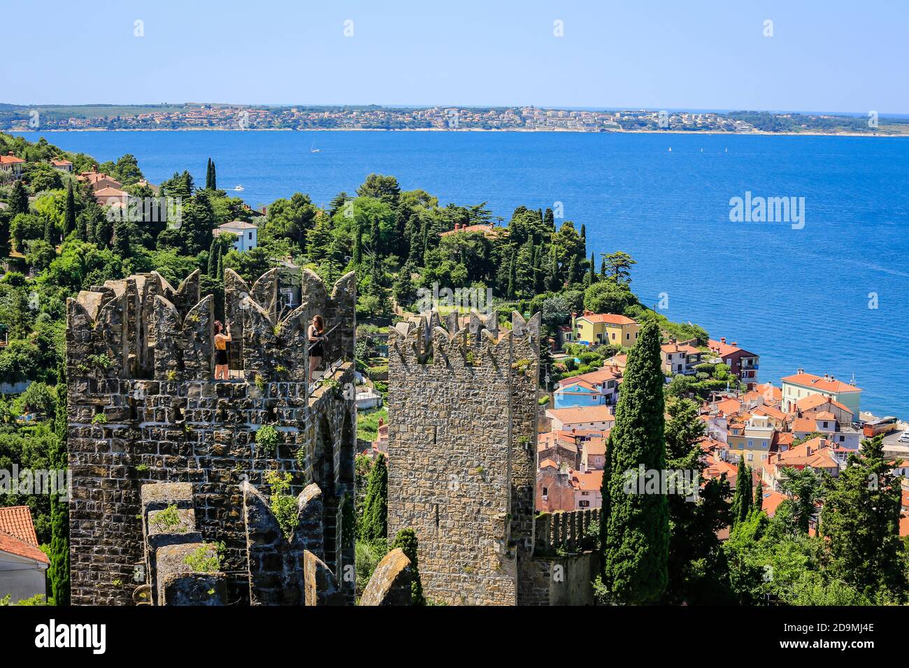 Piran, Istrien, Slowenien - Stadtübersicht, Blick über die Stadtmauer und die Dächer der Hafenstadt am Mittelmeer, Touristen fotografieren sich auf der historischen Stadtmauer. Stockfoto