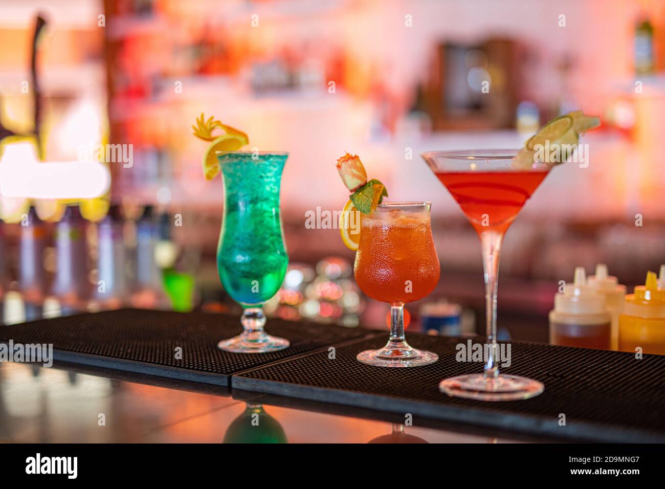 Bunte Cocktails an der Bar. Tropische Cocktails auf dem Restauranttisch, fertig zum Servieren. Nachtleben Party, Bar Drink Hintergrund, verschwommene Flaschen Stockfoto