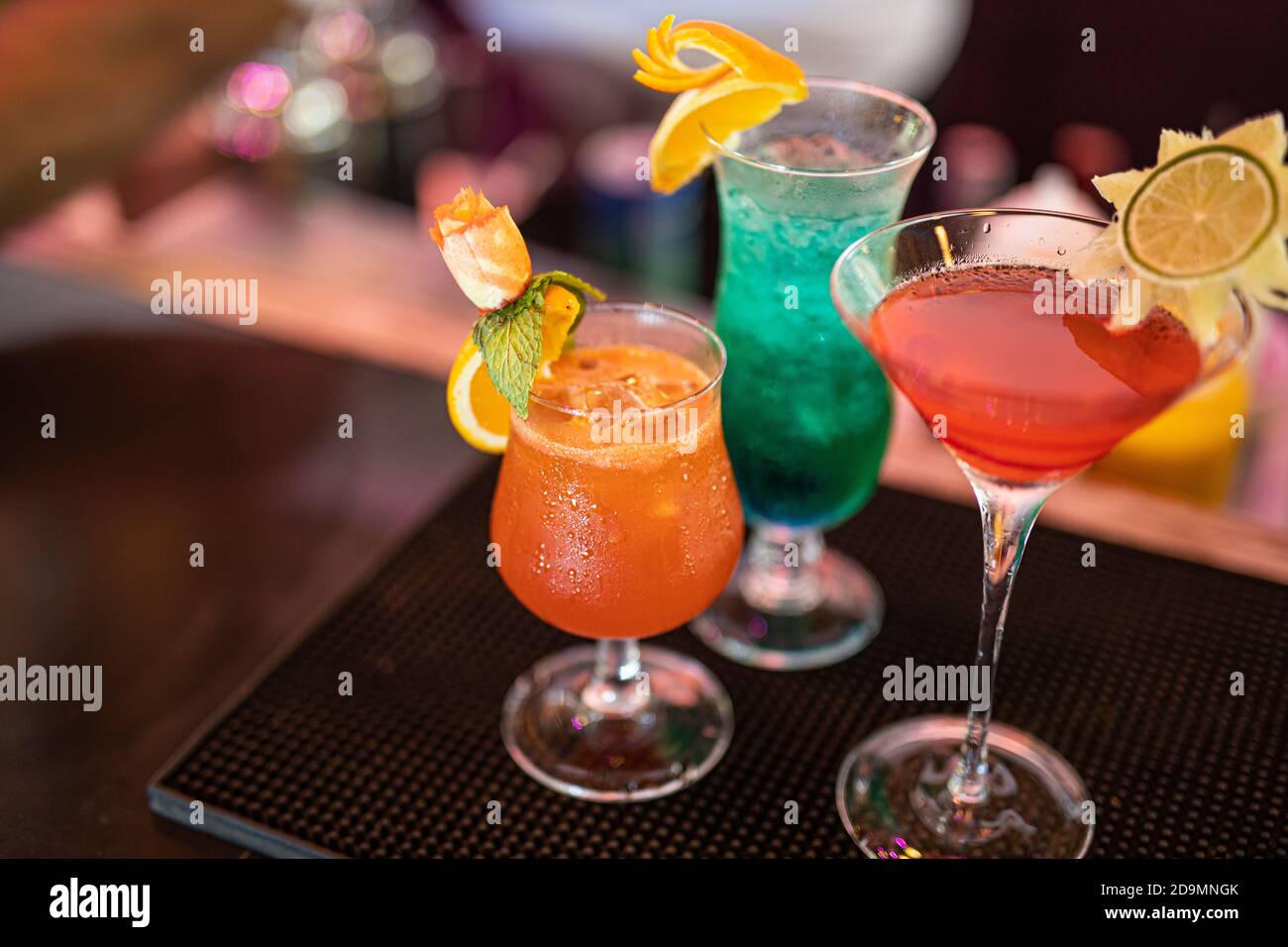 Bunte Cocktails an der Bar. Tropische Cocktails auf dem Restauranttisch, fertig zum Servieren. Nachtleben Party, Bar Drink Hintergrund, verschwommene Flaschen Stockfoto