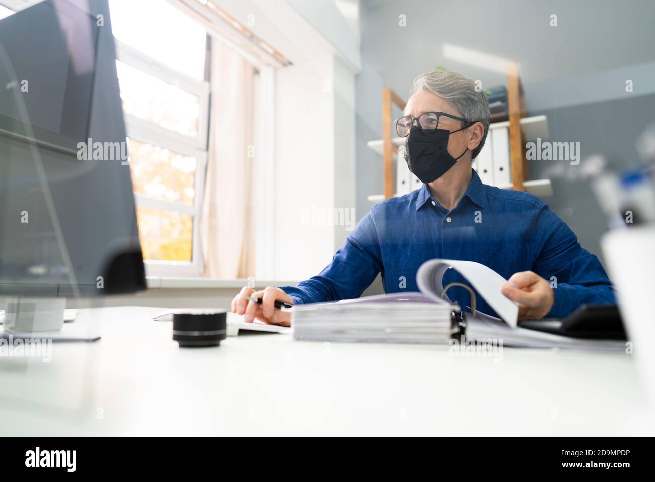 Leitender Buchhalter, Der Mit Der Maske Rechnung In Gesicht Arbeitet Stockfoto