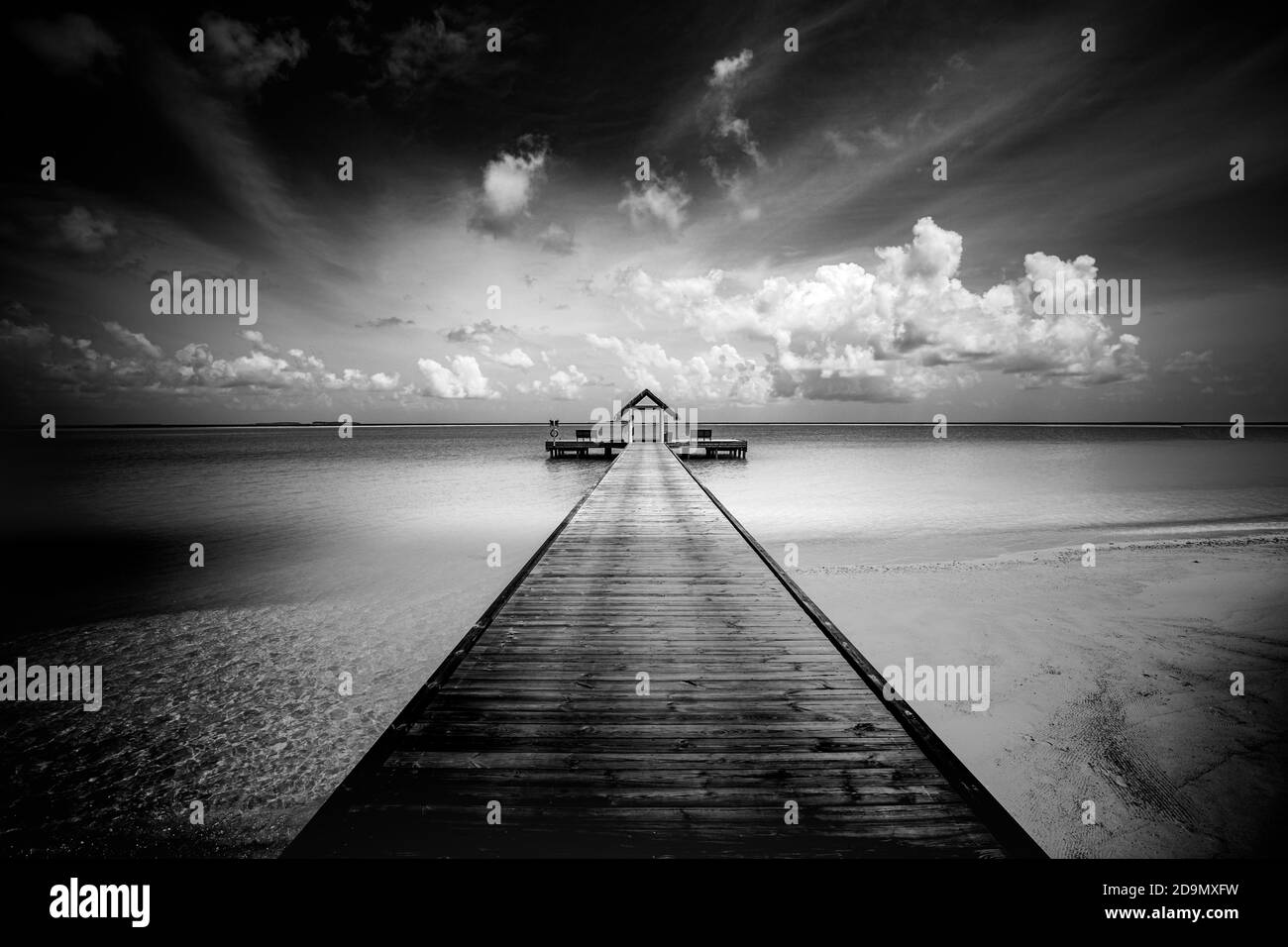 Schwarz-weiße Strandszene. Starke kontrastierte getönte Foto. Dramatische Strandlandschaft mit über Wasser Villa Bungalow auf den Malediven. Künstlerische Landschaft Stockfoto