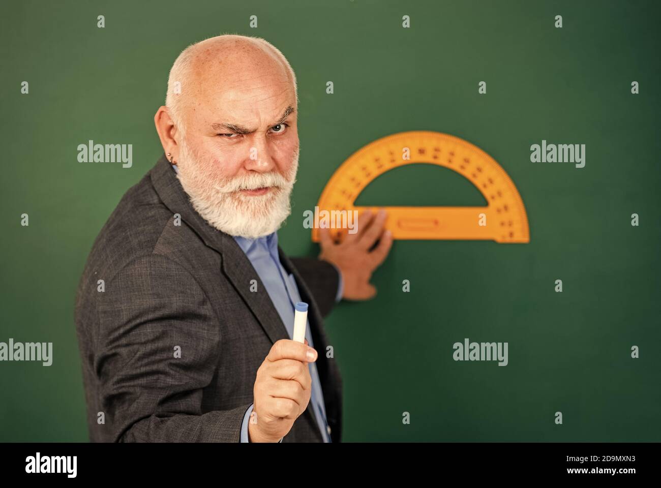 Ernst und streng. Heimlernen. Lehrer für ältere Männer verwenden ein Werkzeug für Fortziehende. Bärtiger Tutor zieht mit einem Lineal auf die Tafel. Zurück zur Schule. Lieblingsfach und -Disziplinen. Ausbildung in der Schule. Stockfoto