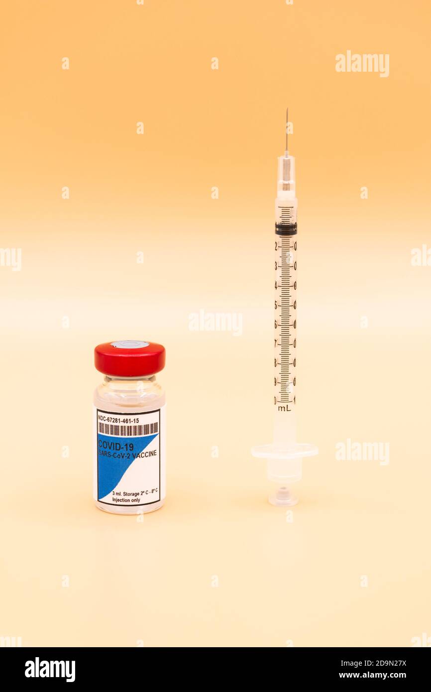 Ein Fläschchen des COVID-19-Impfstoffes mit einer Spritze, die aufrecht daneben auf einem orangefarbenen Hintergrund platziert ist. Coronavirus-Konzept Stockfoto