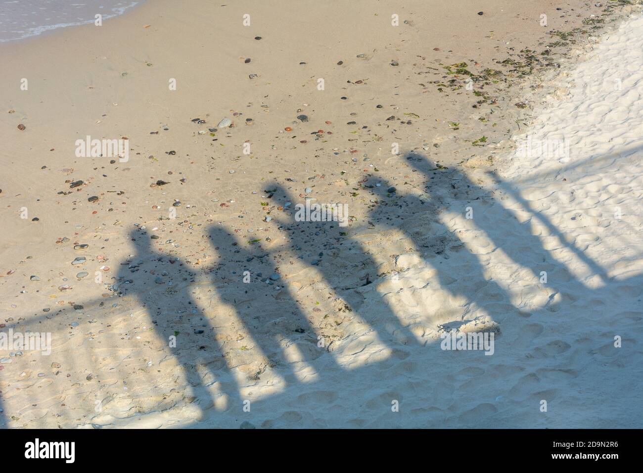 Schatten von Menschen auf Sand in der Nähe des Meeres. Konzept der Erinnerung, Abschied von Angehörigen, Abschied von einer anderen Realität, Tod. Stockfoto