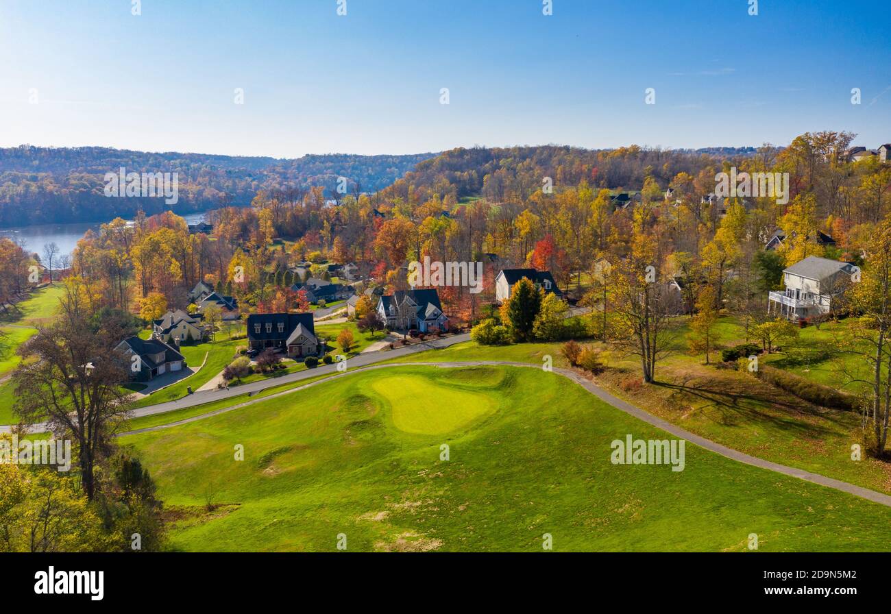 Luftdrohne Panorama von Einfamilienhäusern zwischen Golf gesetzt Fairway und Grüns am See im Herbst Stockfoto