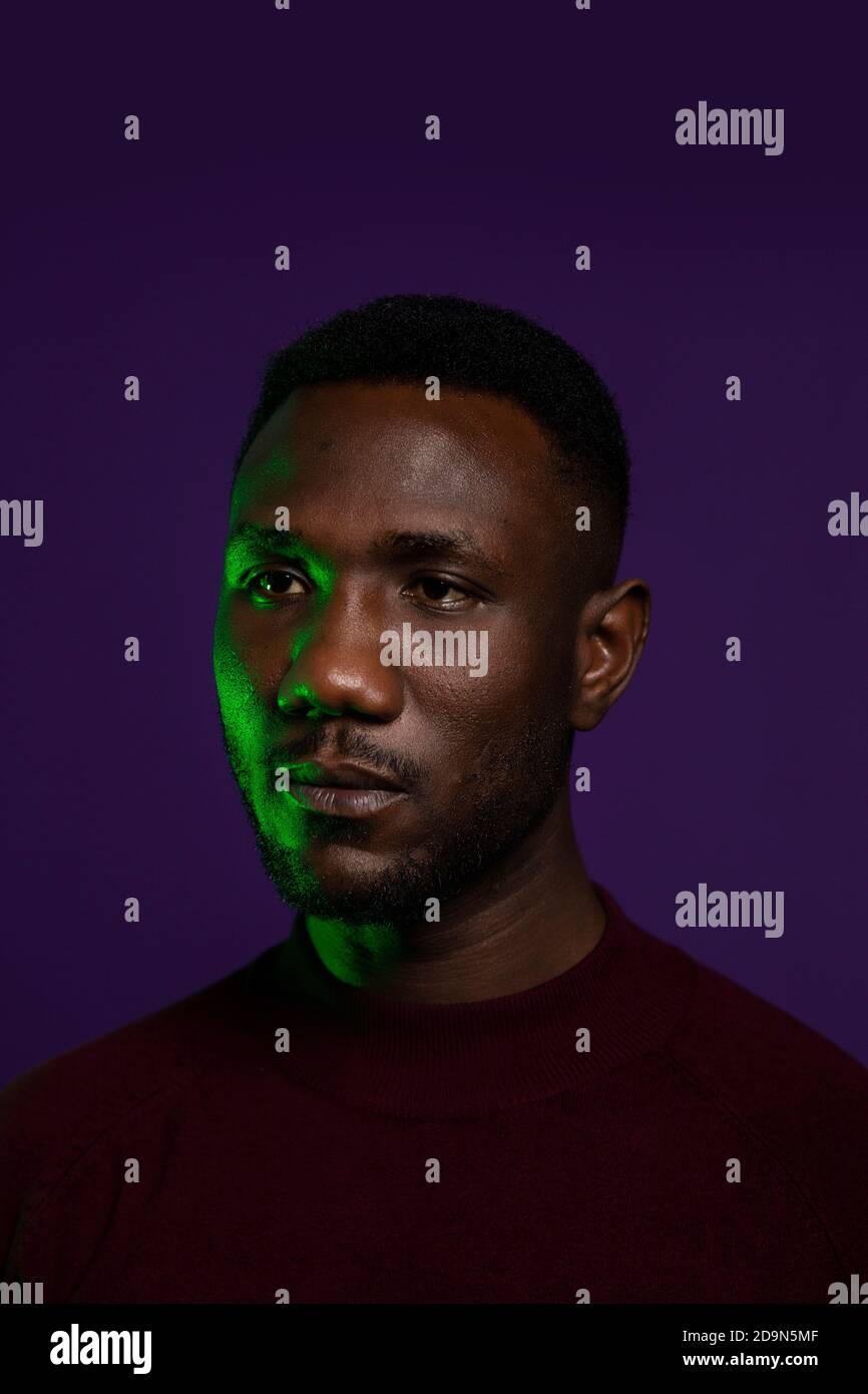 Gesicht eines schönen afrikanischen Mannes mit neutralem Gesichtsausdruck. Mittlere Aufnahme. Isolierter Hintergrund. Hochformat. Wegschauen. Stockfoto