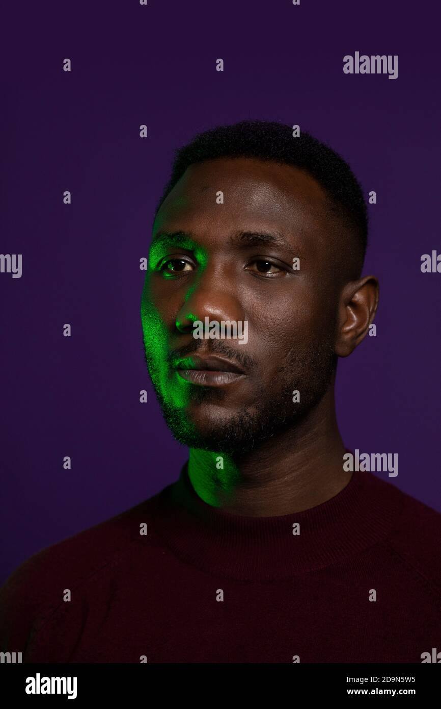 Gesicht von schönen schwarzen Mann mit neutralen Gesichtsausdruck. Mittlere Aufnahme. Isolierter Hintergrund. Hochformat. Wegschauen. Stockfoto