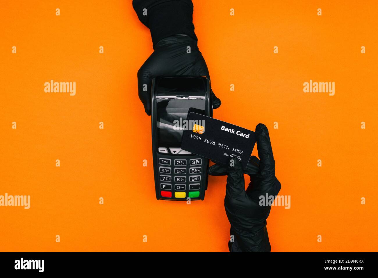 Ein Mann in schwarzen Einweghandschuhen hält ein drahtloses Bankzahlungsterminal in der Hand. Der Kunde bezahlt den Kauf per Kreditkarte. Sicheres Einkaufen Stockfoto