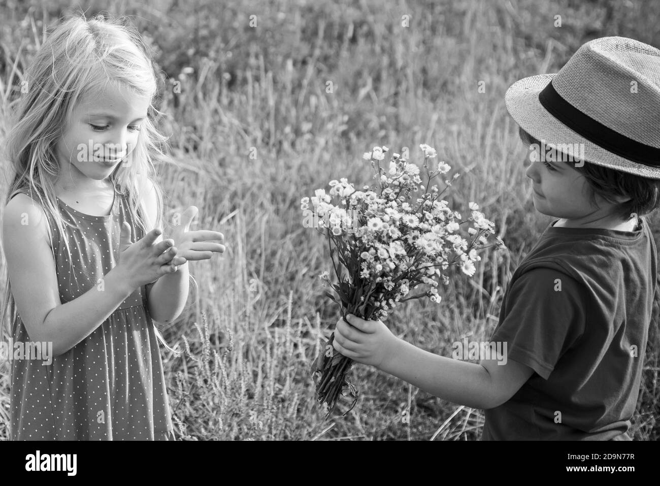 Abenteuer und Ferien Kinder Konzept. Glückliche Kinder Mädchen und Junge Umarmung auf der Wiese im Sommer in der Natur. Kleine Engel in der Liebe. Alles gute zum Valentinstag Stockfoto