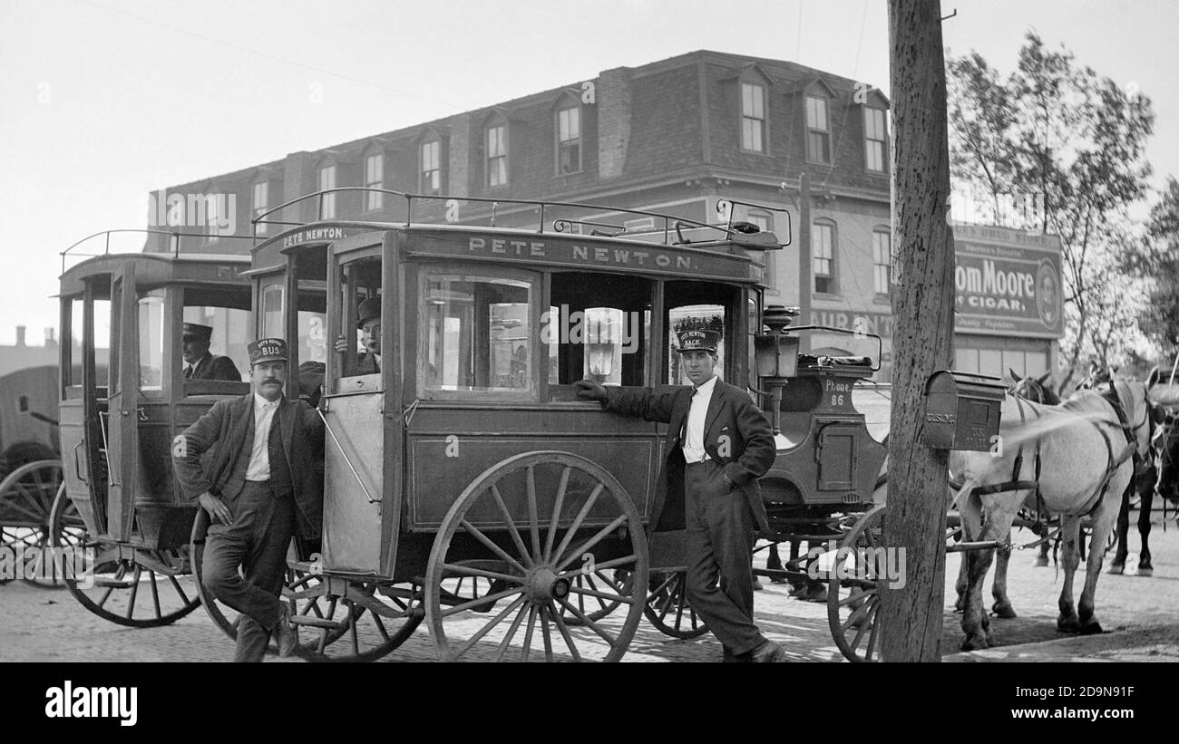 1910ER ZWEI MÄNNER FAHRER BLICK AUF KAMERA UND PFERD GEZOGEN WAGGONS WARTEN AUF PASSAGIERE AM BAHNHOF EMPORIA KANSAS USA - Q45712 CPC001 HARS JOBS TRANSPORT VEREINIGTE STAATEN KOPIERRAUM FULL-LENGTH PERSONEN VEREINIGTE STAATEN VON AMERIKA MÄNNER KANSAS RÄDER TRANSPORT B&W NORTH AMERICA NORTH AMERICAN SKILL OCCUPATION SKILLS SÄUGETIERE KUNDE SERVICE KRAFTFAHRZEUG ARBEIT GEZEICHNET BESCHÄFTIGUNG BERUFE WAGEN MITARBEITER EMPORIA BUSSE SÄUGETIER MITTLEREN ERWACHSENEN MITTLEREN ERWACHSENEN MANN TAXIS TRANSIT SCHWARZ UND WEISS KAUKASISCHE ETHNIZITÄT ARBEIT KRAFTFAHRZEUGE ALTMODISCH Stockfoto
