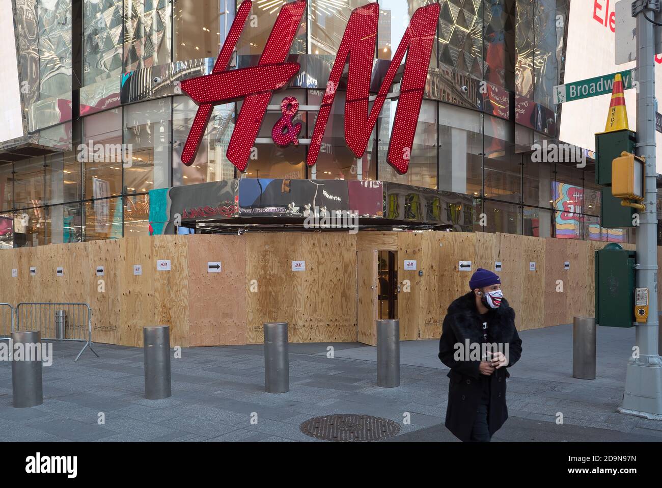 Ein Mann mit einer Maske verlässt einen aufgestiegen H&M-Laden am Times Square. Stockfoto