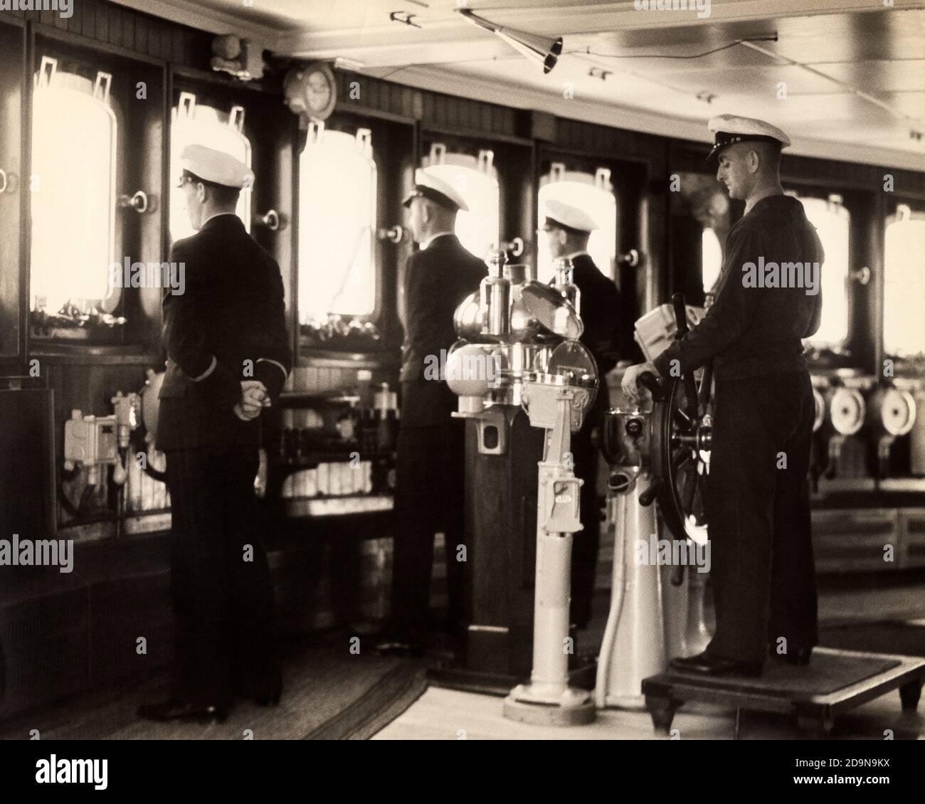 OFFIZIERE DER 1930ER JAHRE UND BESATZUNG ANONYME MÄNNER IN UNIFORM IM DIENST AUF DER BRÜCKE VON OCEAN LINER KREUZFAHRTSCHIFF DIE SS EUROPA AUF DER ATLANTIKÜBERQUERUNG - S5580 HAR001 HARS STEUERRUDER BORD UND DER STOLZ DER FÜHRUNGSRICHTUNG IN DER AUF DIE AUTORITÄT BERUFE ANONYM EUROPA OFFIZIERE BINNACLE ZUSAMMENARBEIT MID-ADULT MID-ADULT MAN SS AN BORD SCHWARZ UND WEISS KAUKASISCHEN ETHNIZITÄT PFLICHT HAR001 ALTMODISCHEN SCHIFF Stockfoto