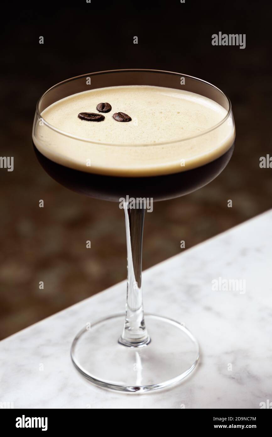 Espresso Martini garniert mit drei Kaffeebohnen, auf einem Marmortisch Stockfoto