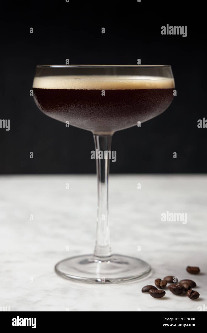 Vorderansicht eines Espresso Martini auf einem Marmortisch. Kaffeebohnen-Dekoration Stockfoto