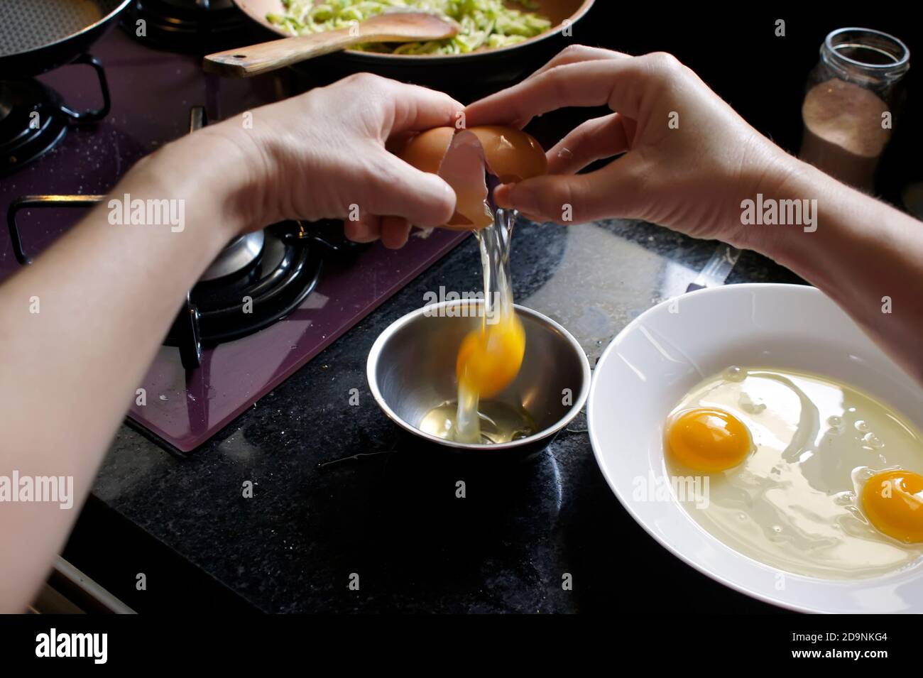 Frau bricht Eier, um Omelette zu Hause zu machen. Konzentrieren Sie sich auf das Ei. Standpunkt Stockfoto