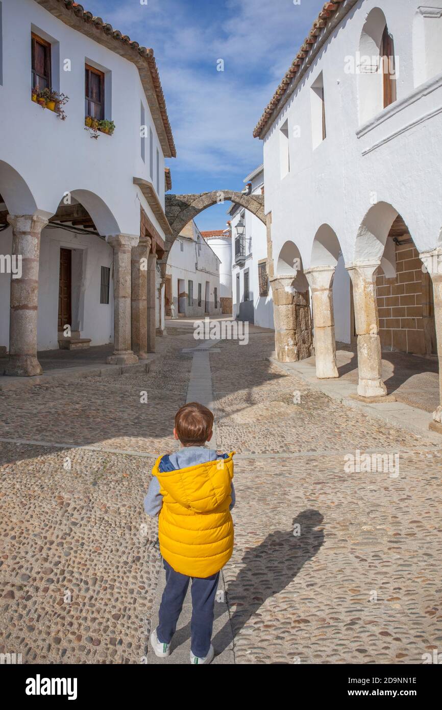 Beeindruckender Platz von Garrovillen de Alconetar, Caceres, Extremadura, Spanien. Kind Junge beobachten eines der quadratischen Tore Stockfoto