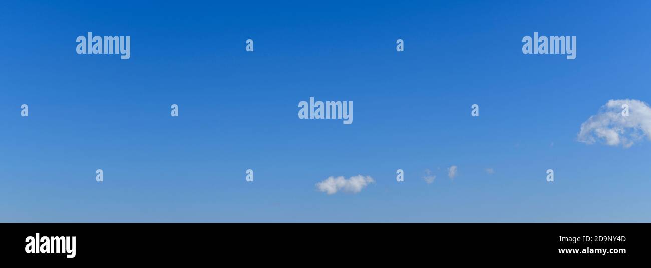 Ein Panoramabild eines klaren blauen Himmels mit einem weichen, weichen Übergang und hellweißen schwebenden Wolken, diagonal. Stockfoto