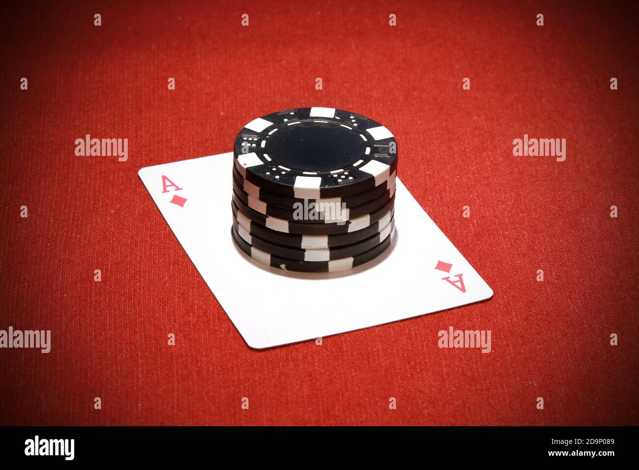 Ein Stapel schwarzer Pokerchips auf einem roten Ass Karte Stockfoto