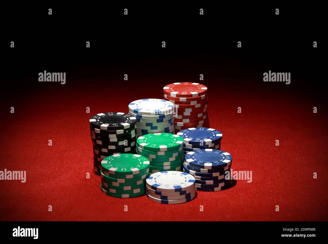 Ein Stapel farbenfroher Pokerchips auf einem roten Tisch Stockfoto