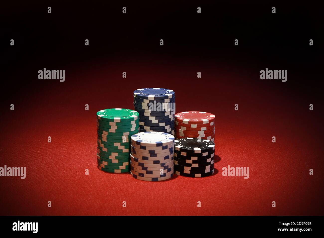 Die Stapel von bunten Pokerchips auf einem roten Tisch Stockfoto