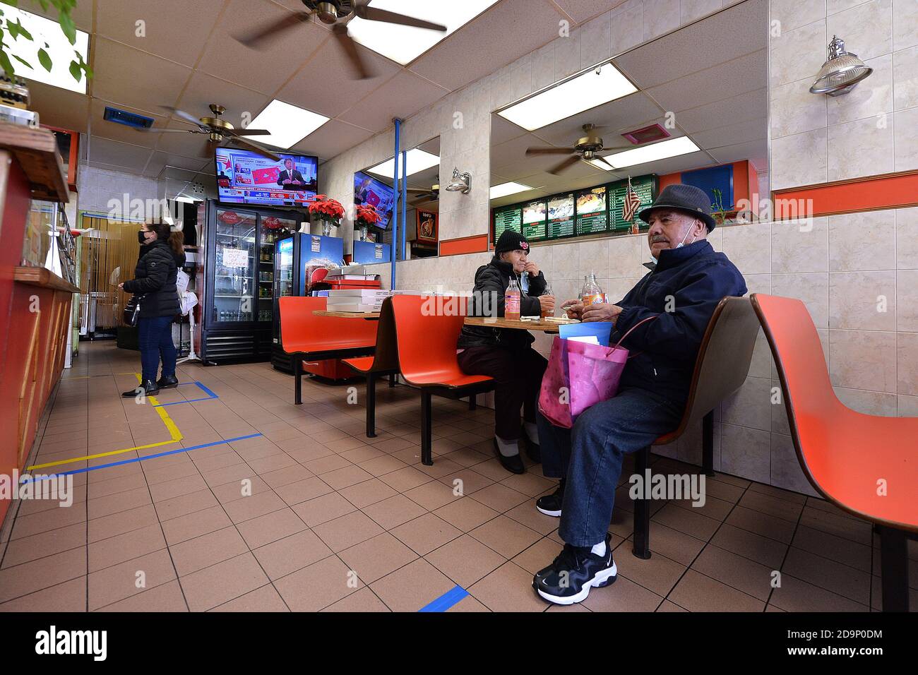 New York City, USA. November 2020. Ein Kunde gibt eine Bestellung in einem Pizzalabor auf, während ein hinter dem Fernseher hängender Flachbildschirm auf CNN's laufende Berichterstattung über die Präsidentschaftswahlen 2020 im Stadtteil Queens von New York, NY, 6. November 2020 abgestimmt ist. Das Ergebnis der Präsidentschaftswahlen, die am 3. November zwischen dem demokratischen Präsidentschaftskandidaten Joseph Biden und dem amtierenden US-Präsidenten Donald Trump abgehalten wurden, hängt von der Zählung der Briefwahl in bestimmten Schlüsselstaaten ab. (Anthony Behar/Sipa USA) Quelle: SIPA USA/Alamy Live News Stockfoto
