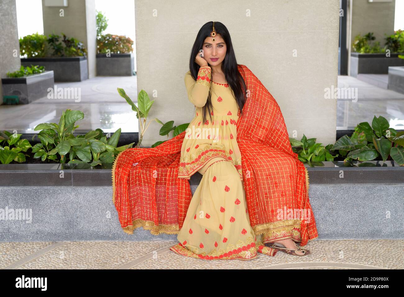 Junge Frau trägt traditionelle indische Kleidung während des Sitzens Stockfoto