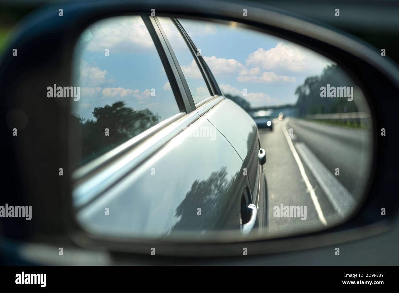 Spiegelung im Seitenspiegel eines Autos, das auf der Autobahn