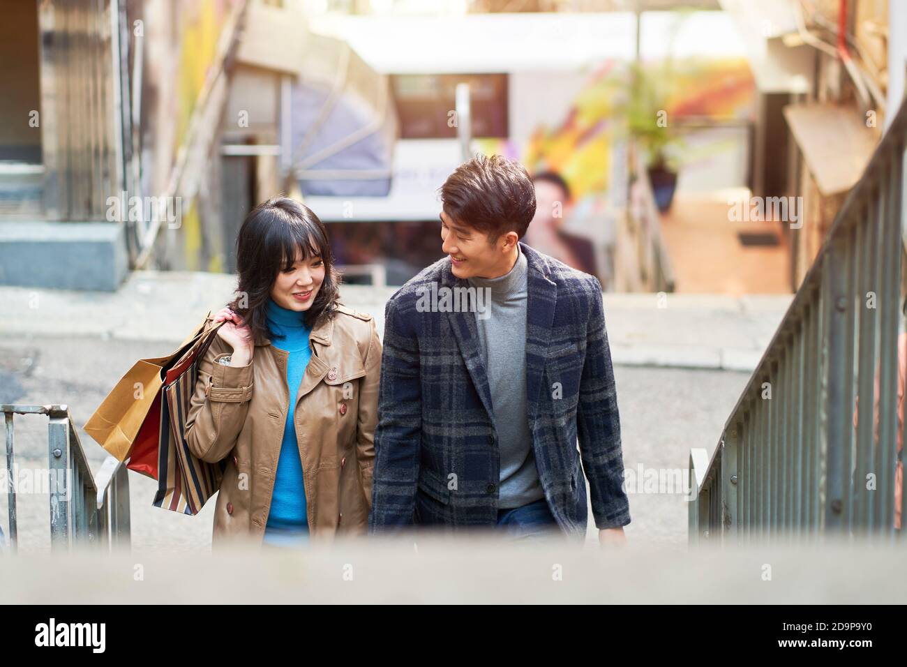Glücklich junge asiatische Paar zu Fuß im Gespräch mit Einkaufstaschen in Hand Stockfoto