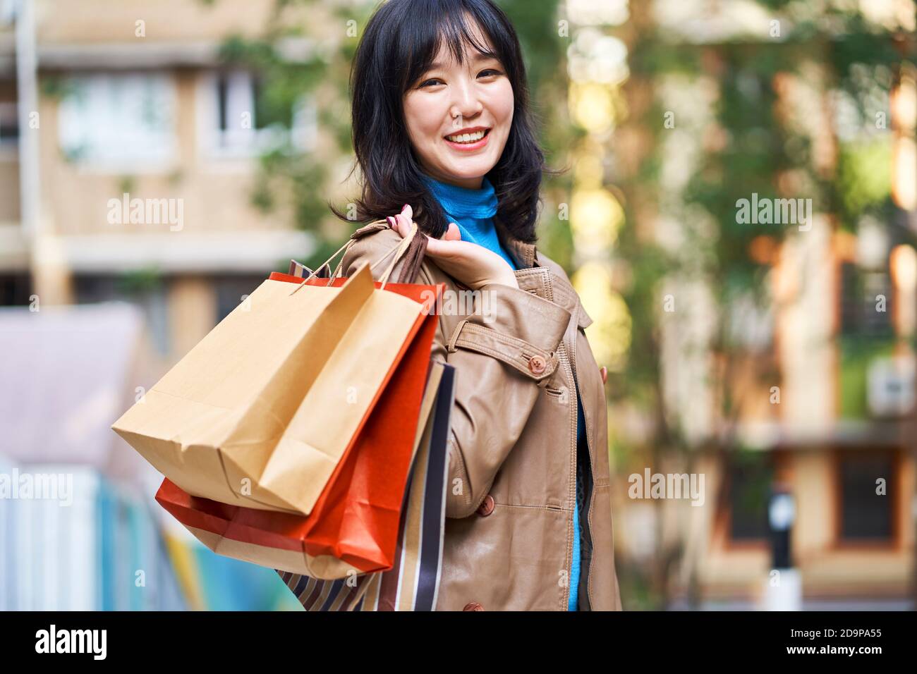 Außenportrait einer jungen asiatischen Frau mit Einkaufstaschen In der Hand Stockfoto