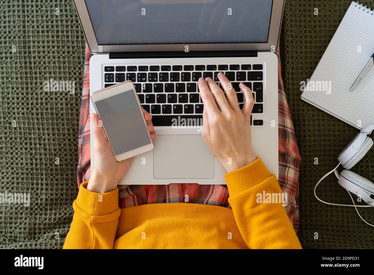 Online-Shopping. Frau, die Code und Passwort aus der Nachricht auf dem Telefon auf dem Laptop eingibt. Stockfoto