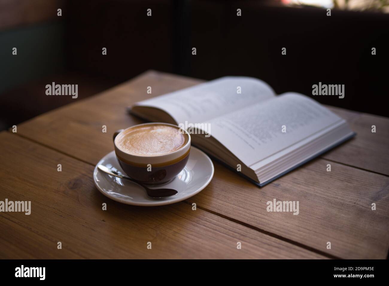 Flacher weißer Kaffee mit Buch im Coffee Shop auf dem Tisch - Kaffee Kunst - Latte Kaffee Stockfoto