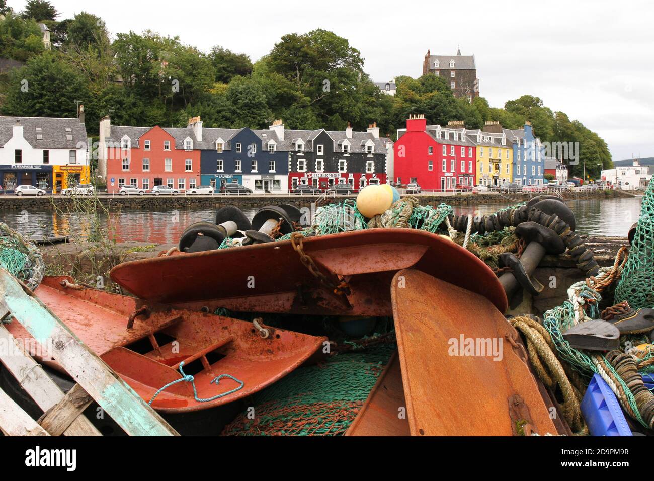 Tobermory auf der Isle of Mull, Argyll und Bute, Schottland. Die Hafenfront mit farbigen Häusern von der Hafenmauer mit Fischerausrüstung aufgestapelt. Stockfoto