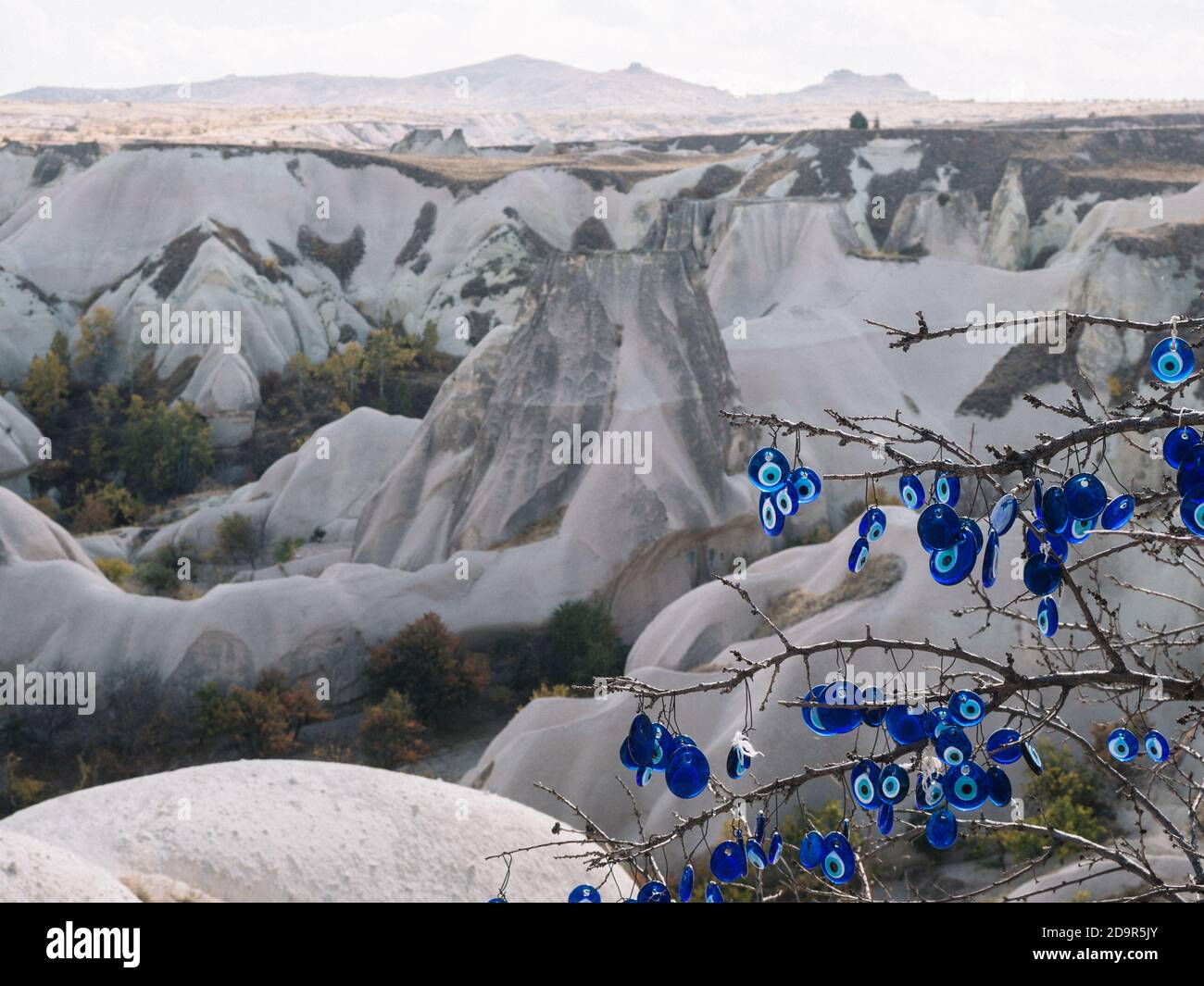 https://c8.alamy.com/compde/2d9r5jy/turkisches-nazar-amulett-blaues-auge-hangt-an-einem-baum-vor-dem-hintergrund-der-berglandschaft-von-kappadokien-aus-blauem-glas-2d9r5jy.jpg